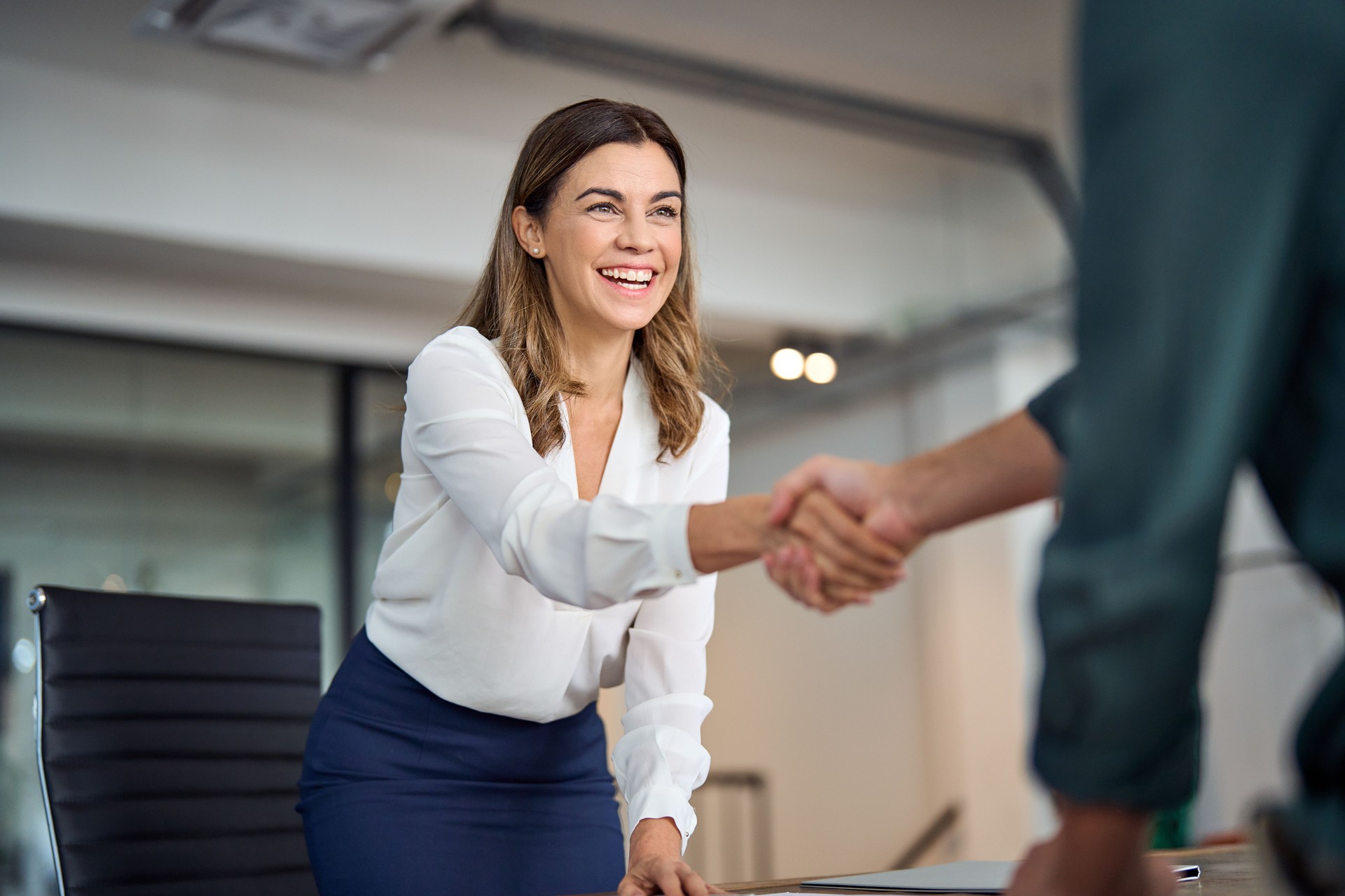 Heureuse femme d’affaires d’âge moyen manager poignée de main accueillant le client au bureau.