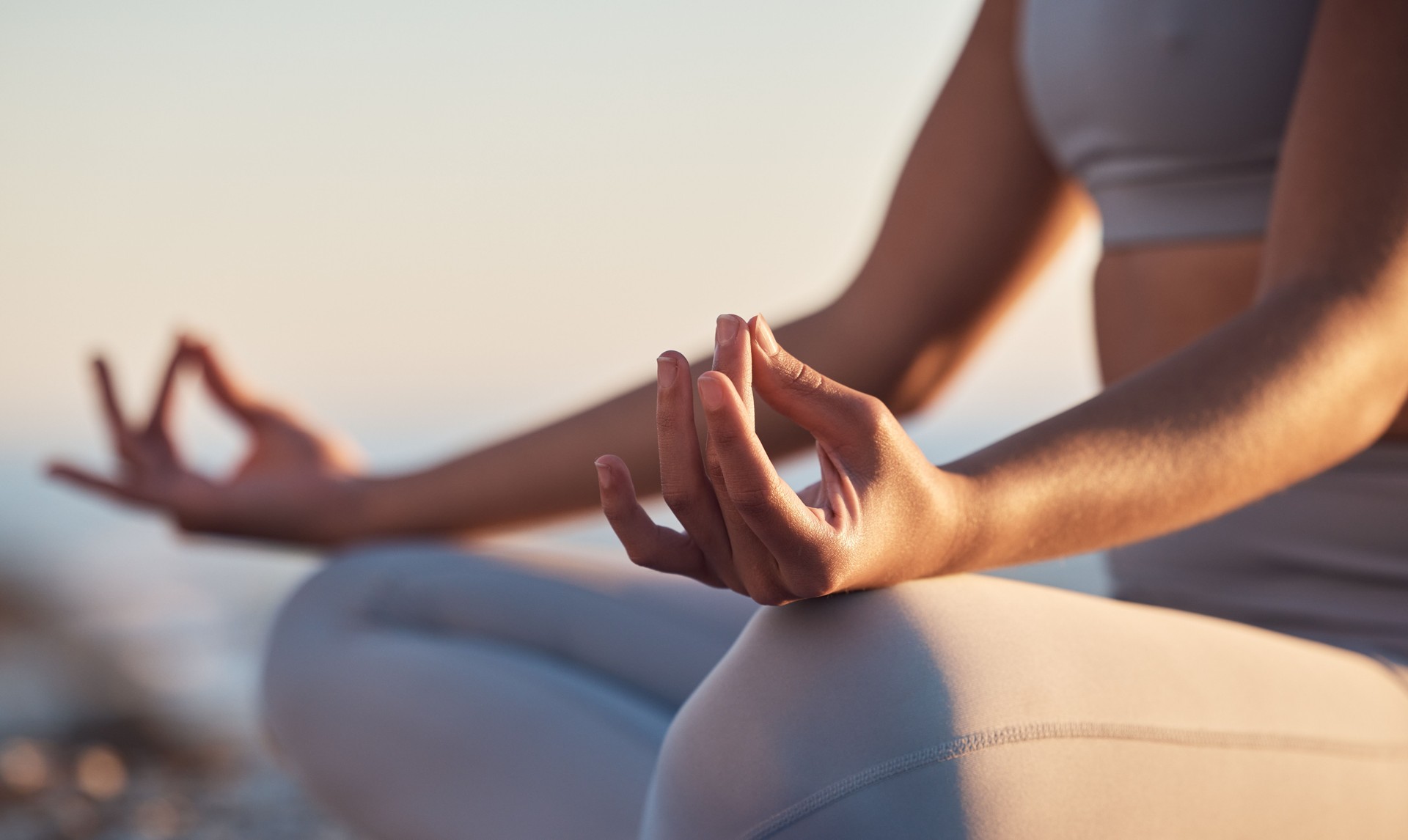 La femme, les mains ou le lotus posent la méditation sur la plage au coucher du soleil, l’océan ou la mer en santé mentale, entraînement de l’esprit ou équilibre des chakras. Zoom, paix ou yogi zen dans le mudra calme, relaxer yoga bien-être ou g